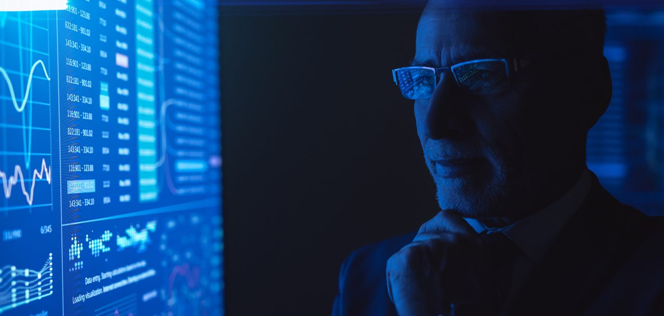 The man standing near the blue screen with chart in the dark room