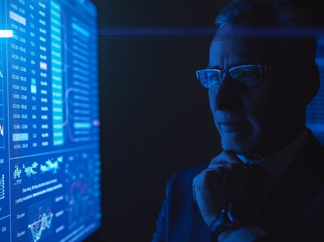 The man standing near the blue screen with chart in the dark room The man standing near the blue screen with chart in the dark room