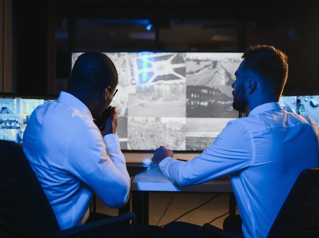 Two male security guards looking at computer screen while one of them explaining detail of video Two male security guards looking at computer screen while one of them explaining detail of video