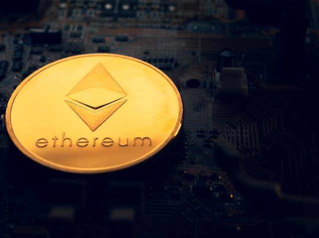 A golden coin with ethereum symbol on a mainboard.