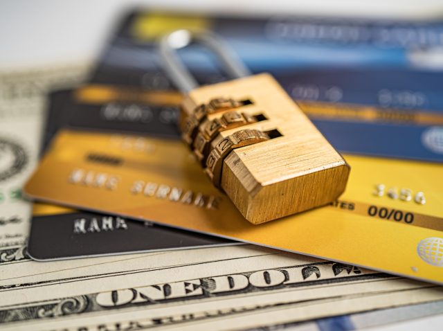 Credit card with password key lock on US dollar background.