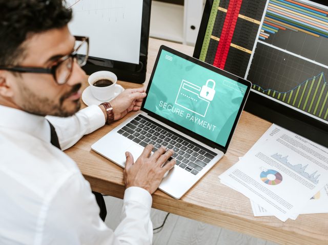 selective focus of bi-racial trader using laptop with secure payment letters