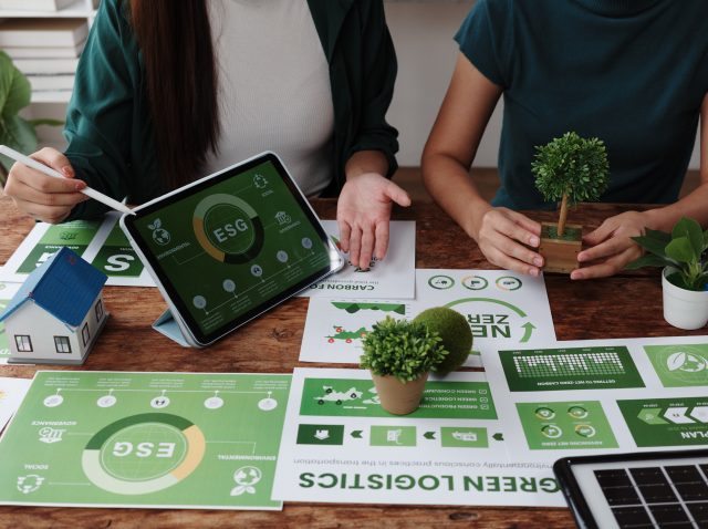 Businesswomen planning environmental social and governance strategy using tablet and charts