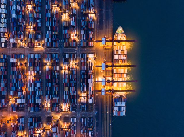 Aerial top view of container cargo ship in the export and import business and logistics international goods in urban city. Shipping to the harbor by crane in Victoria Harbour, Hong Kong City at night. Aerial top view of container cargo ship in the export and import business and logistics international goods in urban city. Shipping to the harbor by crane in Victoria Harbour, Hong Kong City at night.