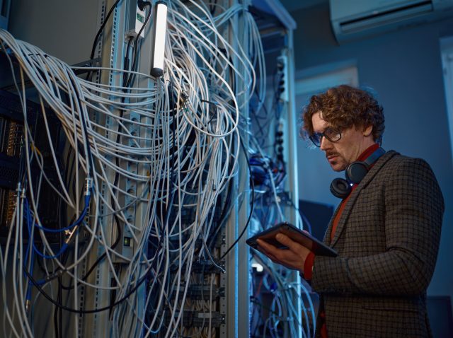 Male IT technical specialist makes a diagnosis in server room