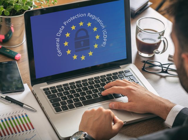 Man working with a computer, General Data Protection Regulation and European Union flag on the screen Man working with a computer, General Data Protection Regulation and European Union flag on the screen