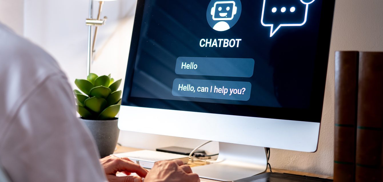 Office worker typing on a computer keyboard interacting with a chatbot on a computer screen, providing automated customer support using future technology