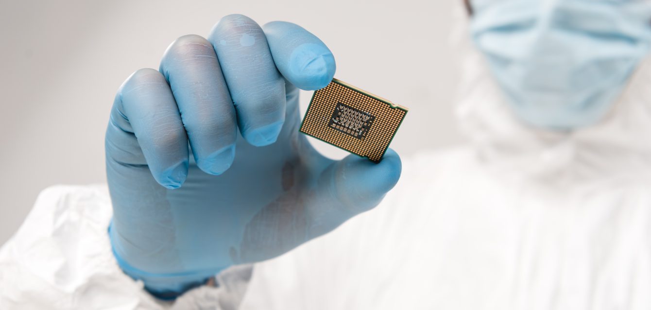 selective focus of microchip in hand of scientist wearing latex glove on grey background