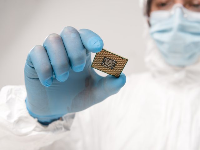 selective focus of microchip in hand of scientist wearing latex glove on grey background selective focus of microchip in hand of scientist wearing latex glove on grey background